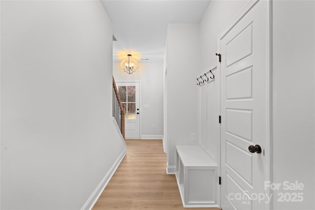 mudroom featuring light wood-style floors, baseboards, and an inviting chandelier