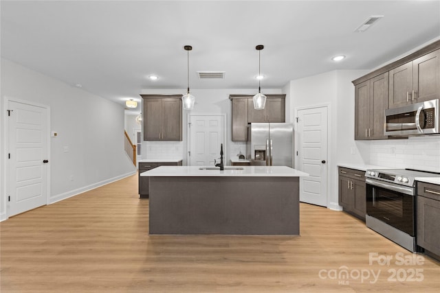 kitchen featuring visible vents, light wood-style flooring, appliances with stainless steel finishes, dark brown cabinets, and a sink