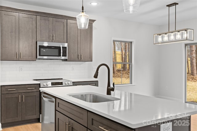 kitchen featuring appliances with stainless steel finishes, light countertops, and a sink