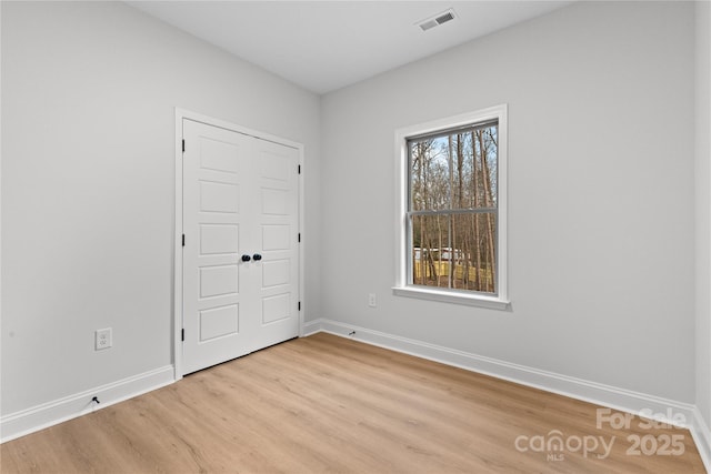 empty room featuring light wood-style floors, baseboards, and visible vents