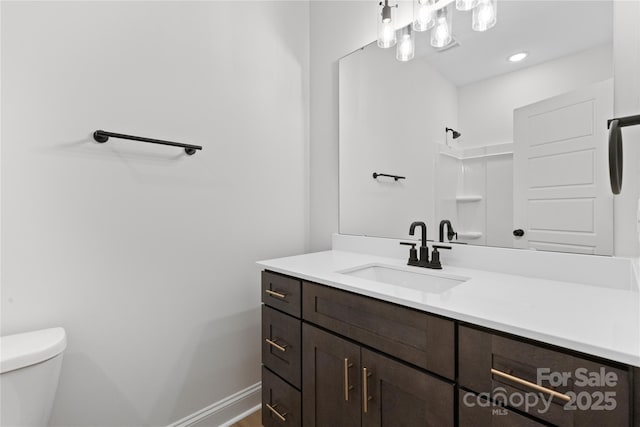 bathroom featuring a shower, vanity, toilet, and baseboards