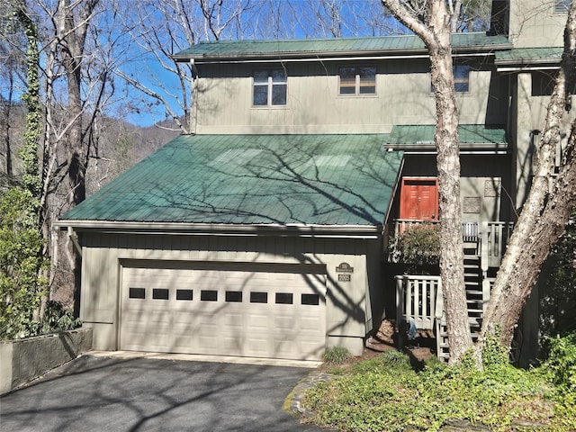 view of front facade featuring a garage, metal roof, and driveway