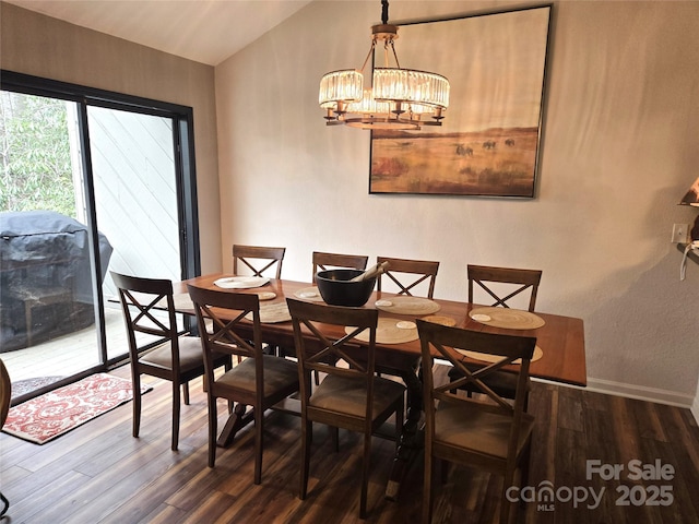 dining room featuring an inviting chandelier, baseboards, vaulted ceiling, and wood finished floors