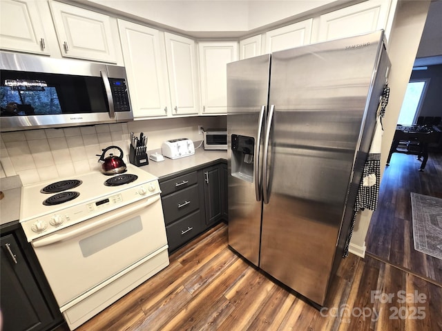 kitchen featuring dark wood-style flooring, light countertops, backsplash, appliances with stainless steel finishes, and white cabinetry