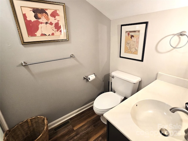 half bathroom featuring visible vents, toilet, vaulted ceiling, vanity, and wood finished floors