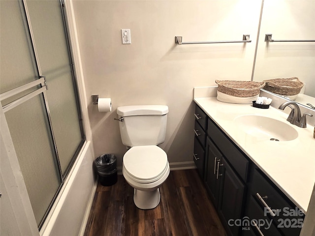 full bath featuring baseboards, toilet, enclosed tub / shower combo, wood finished floors, and vanity