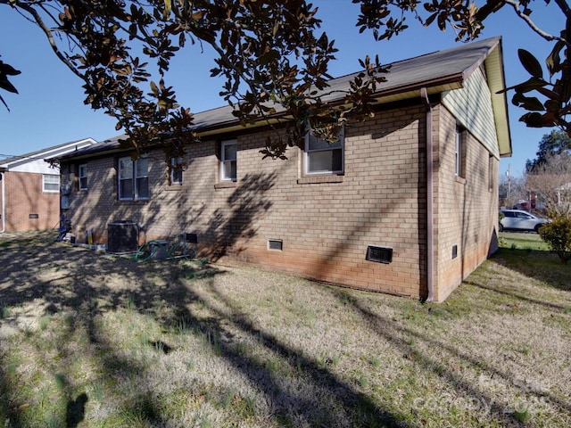 rear view of property featuring crawl space, brick siding, and a yard