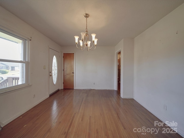 entrance foyer featuring baseboards, a notable chandelier, and light wood finished floors