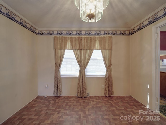 empty room featuring ornamental molding and a notable chandelier