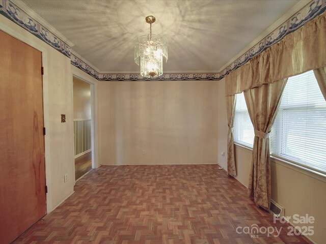 unfurnished room featuring crown molding, a textured ceiling, visible vents, and a notable chandelier