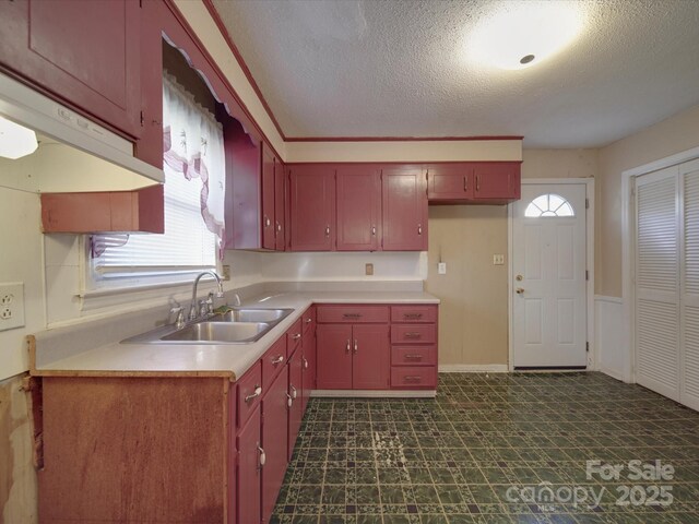 kitchen with dark floors, light countertops, a sink, and a textured ceiling