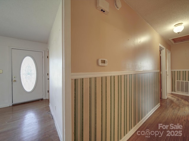 entrance foyer featuring visible vents, a textured ceiling, and hardwood / wood-style floors