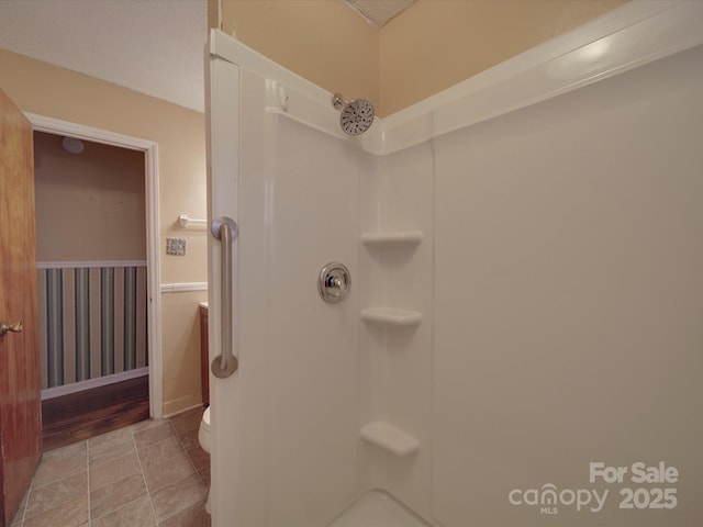 bathroom featuring walk in shower, toilet, and tile patterned floors