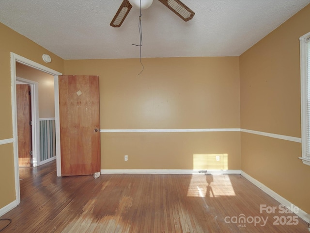 spare room with baseboards, a textured ceiling, visible vents, and wood finished floors