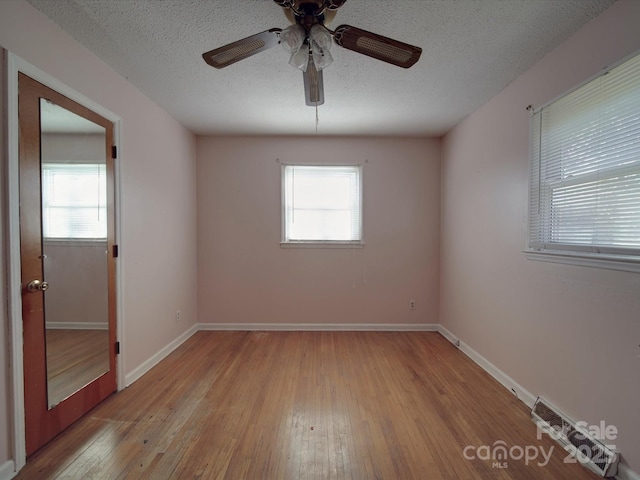 unfurnished room with light wood-type flooring, plenty of natural light, and a textured ceiling