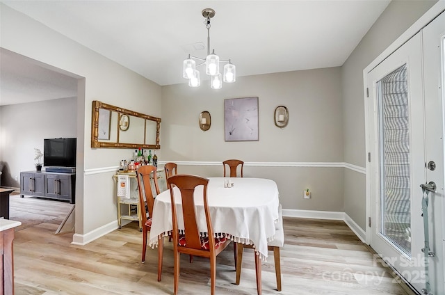 dining room featuring a notable chandelier, light wood-style floors, and baseboards