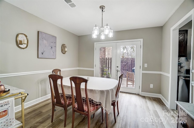 dining room with light wood-type flooring, visible vents, french doors, an inviting chandelier, and baseboards