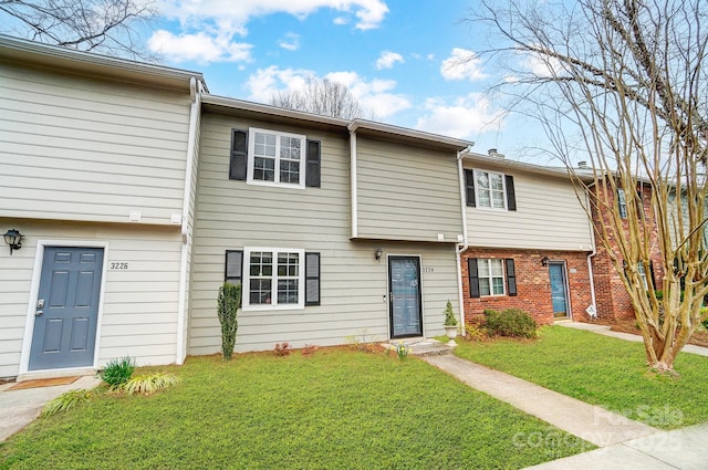 townhome / multi-family property featuring brick siding and a front lawn