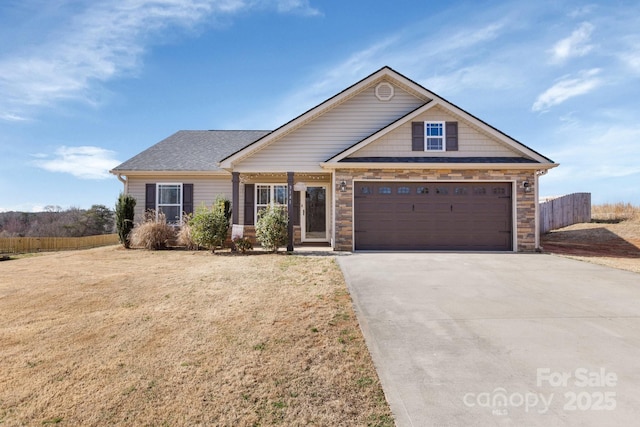 view of front facade with a front yard, stone siding, driveway, and fence