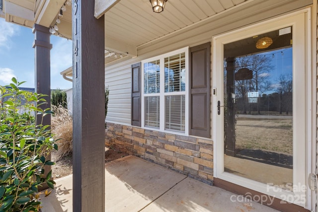 doorway to property featuring stone siding and covered porch