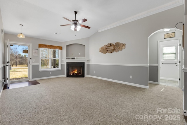 unfurnished living room featuring a lit fireplace, carpet flooring, and a healthy amount of sunlight