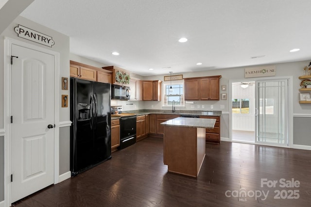 kitchen with brown cabinetry, dark wood-style floors, a kitchen island, black appliances, and recessed lighting