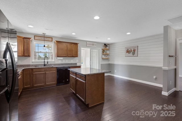 kitchen with black appliances, a kitchen island, dark wood finished floors, and a sink