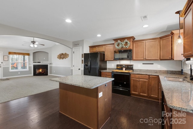 kitchen featuring a sink, visible vents, a center island, black appliances, and brown cabinetry