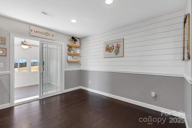 spare room with dark wood-style floors, visible vents, and baseboards