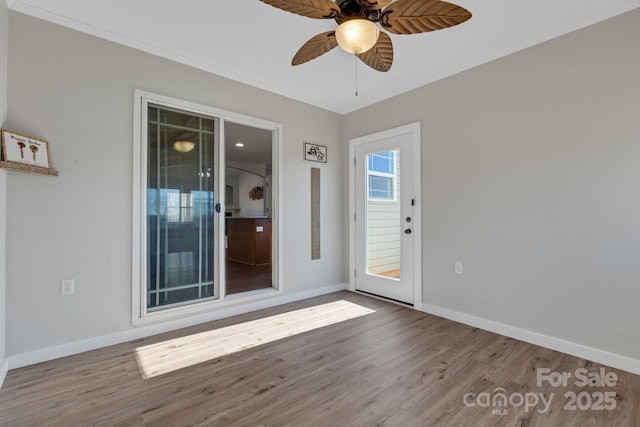 empty room featuring baseboards, ornamental molding, and wood finished floors