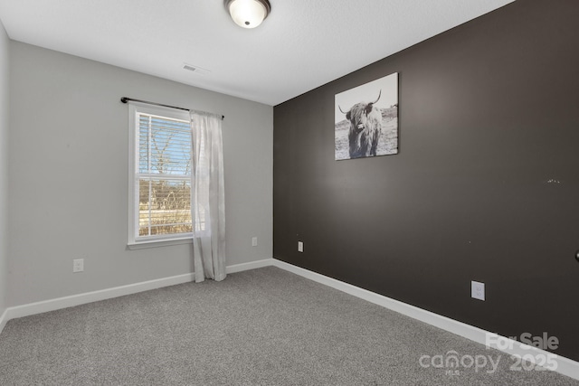 carpeted spare room featuring visible vents and baseboards