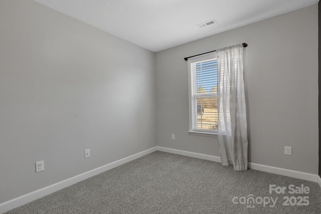 spare room with carpet, visible vents, and baseboards