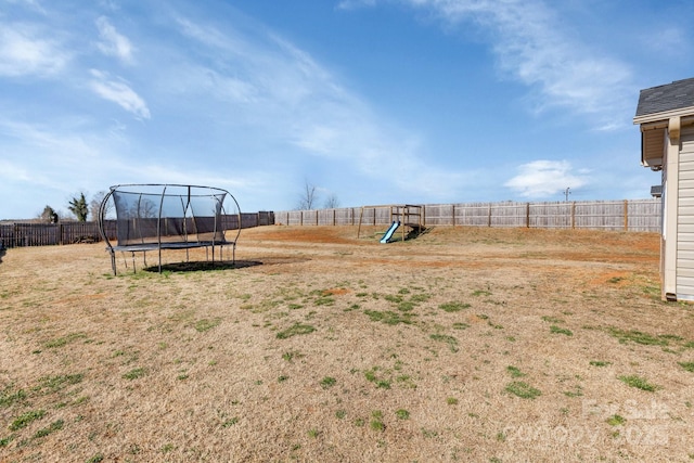 view of yard featuring a fenced backyard, a trampoline, and a playground