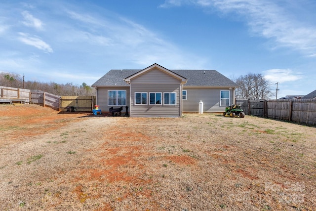 rear view of house featuring a yard and a fenced backyard