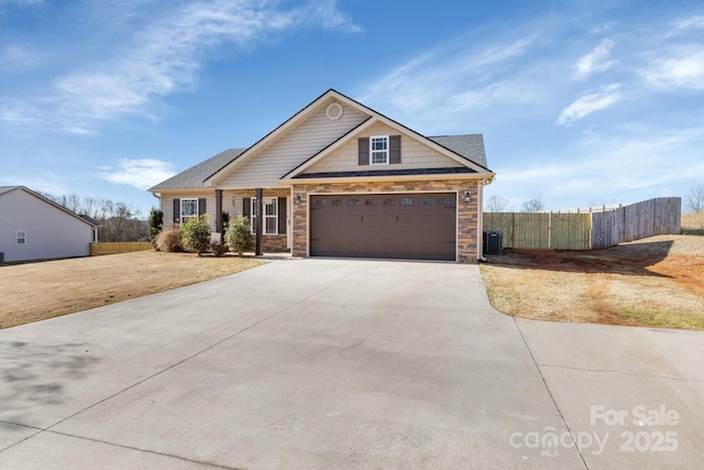 craftsman house featuring central AC unit, stone siding, fence, and concrete driveway