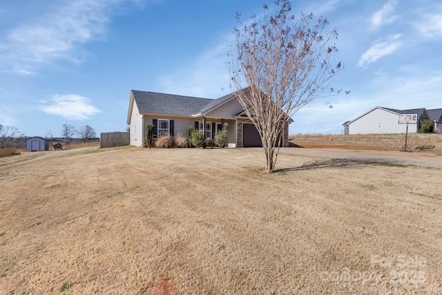 ranch-style house with an attached garage, a storage shed, a front yard, fence, and driveway