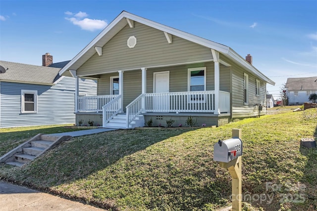 bungalow featuring covered porch, a front lawn, and a chimney