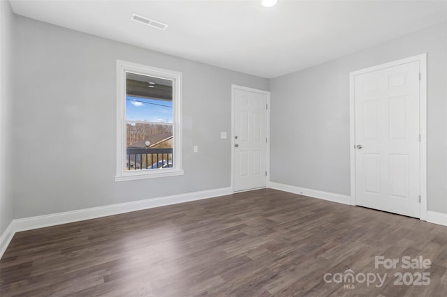 spare room featuring baseboards, visible vents, and wood finished floors