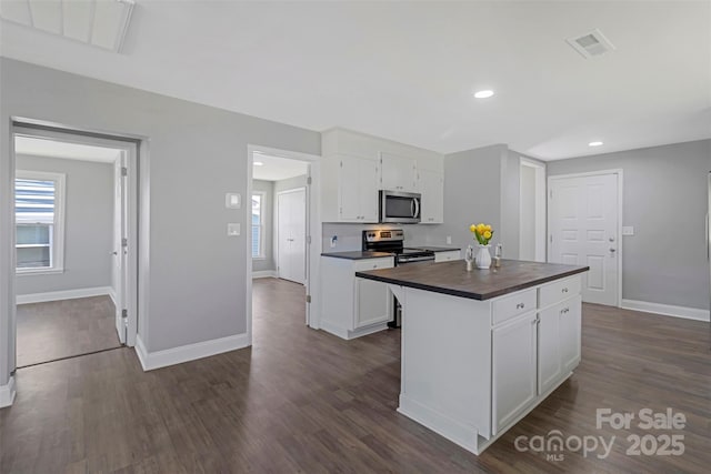 kitchen with stainless steel appliances, visible vents, baseboards, white cabinets, and dark wood-style floors