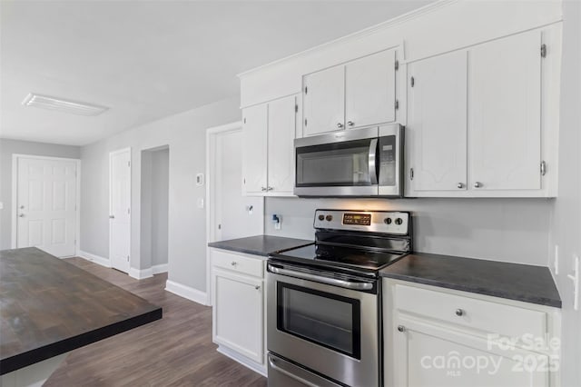 kitchen with dark countertops, appliances with stainless steel finishes, white cabinets, and dark wood finished floors