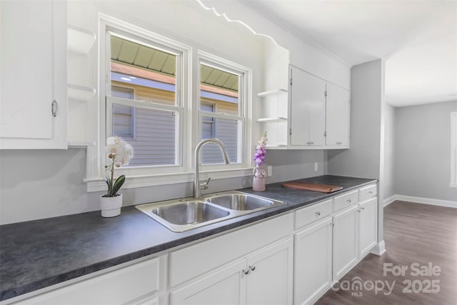 kitchen featuring dark countertops, white cabinets, open shelves, and a sink