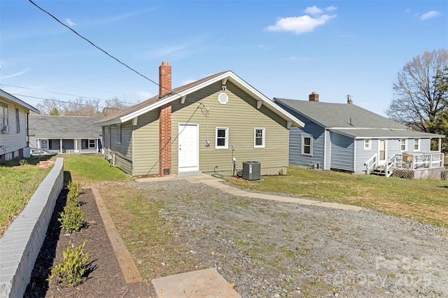 back of house featuring a chimney, a lawn, and cooling unit