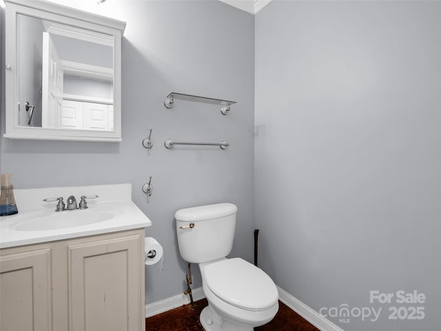 bathroom featuring toilet, baseboards, wood finished floors, and vanity