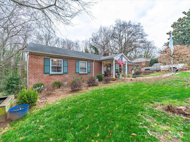 view of front of house with brick siding, a chimney, and a front yard