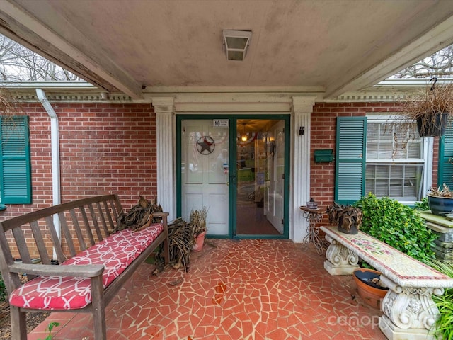 property entrance with a patio and brick siding