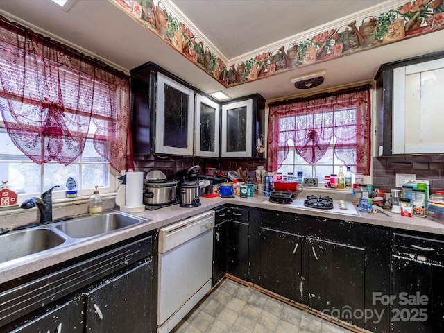 kitchen with crown molding, light countertops, a sink, dark cabinets, and white appliances