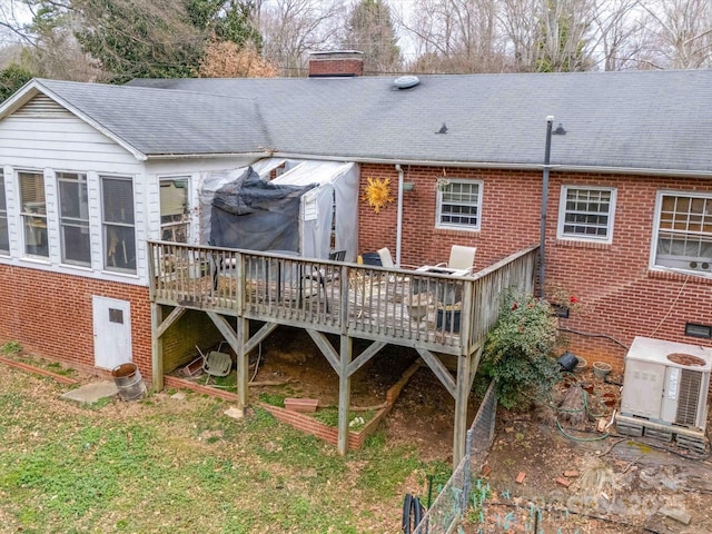 rear view of property with a deck, brick siding, and a chimney