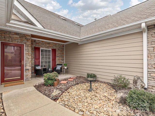 entrance to property with a shingled roof and stone siding