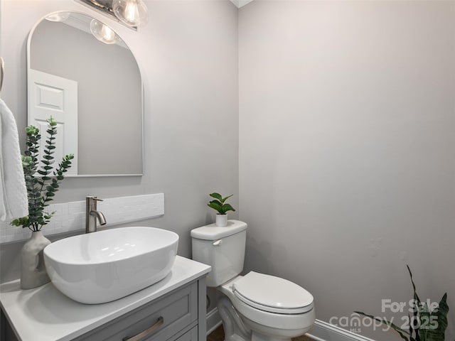 half bath with toilet, vanity, and decorative backsplash