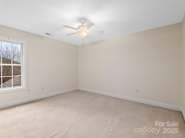 spare room with visible vents, ceiling fan, light carpet, and baseboards